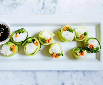 plate with veggie sushi made of cucumber, rice, avocado, and green onion