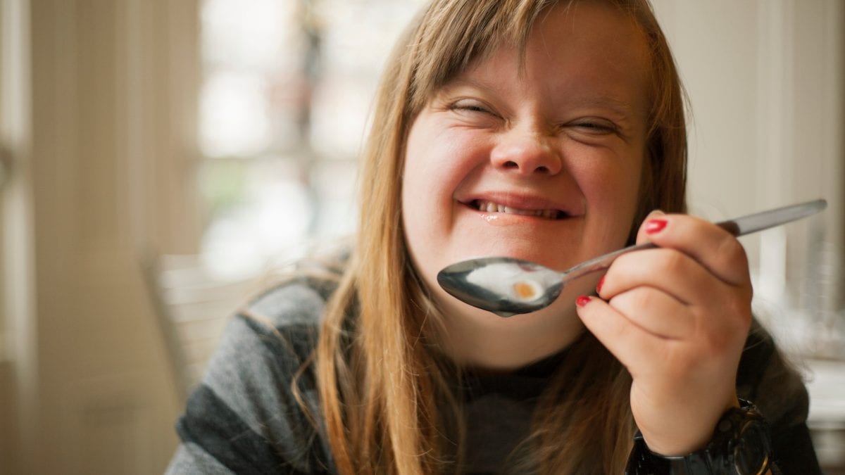 Young woman smiling and holding up spoon