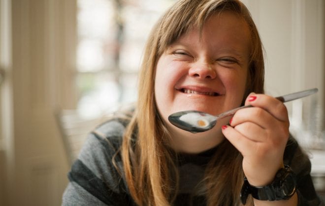 Young woman smiling and holding up spoon