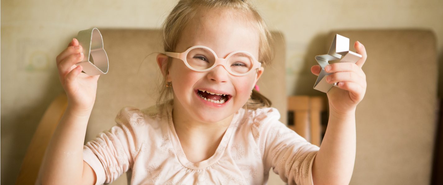 girl with Down syndrome holding up cookie cutters