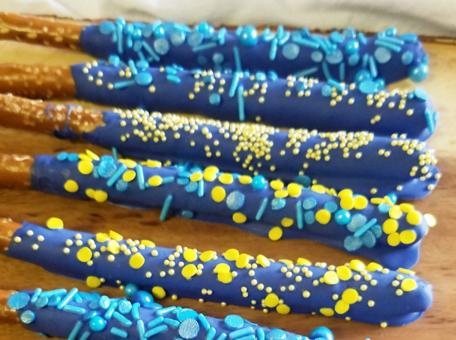 pretzel rods with blue chocolate and blue and yellow sprinkles