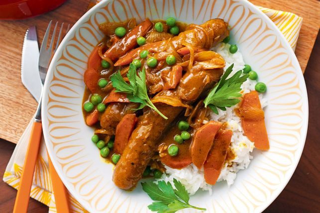 photo of curried sausages on a plate with rice and peas
